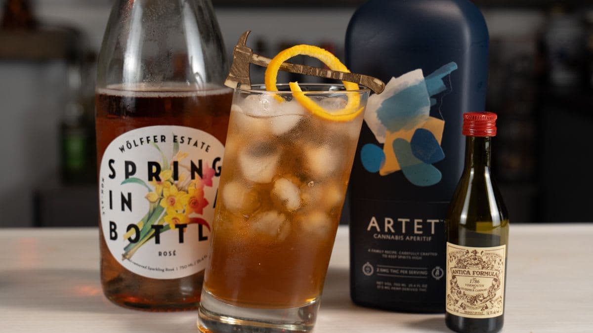 Cannabis Negroni Sbagliato with an orange twist and wooden hatchet garnish, with Artet, Wölffer sparkling rosé, and Carpano Antica bottles